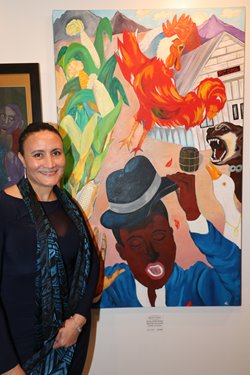 A woman artist stands next to her painting