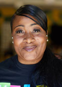 A black woman wearing a t-shirt smiles at the camera