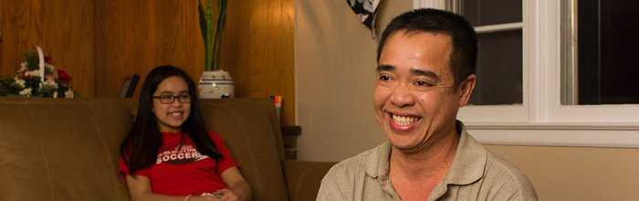 An Asian family sits in the living room of their new home, bought through a shared equity housing model