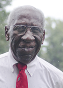 Manfred Reid stands outside, wearing a red tie