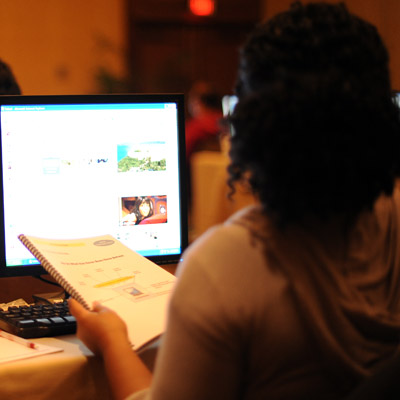 A person sits in front of a computer with a booklet