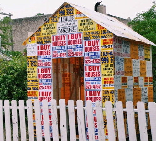 A home covered in "for sale" signs as part of a creative project to highlight issues for cdcb's residents