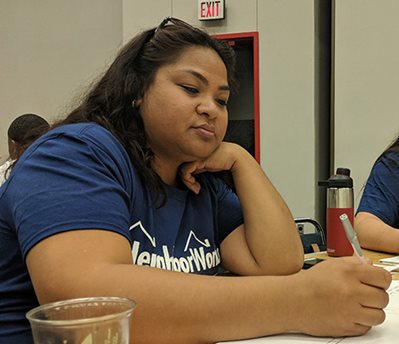 A young woman of color sits at a table, studying