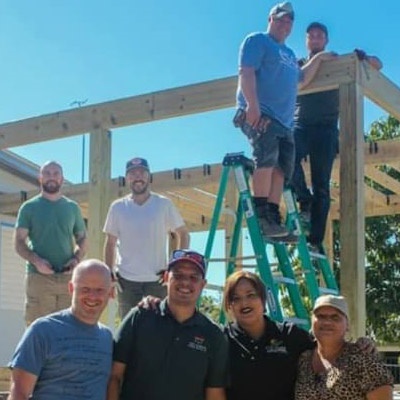 Another team works on housing reconstruction. Just the frame of the house is showing.