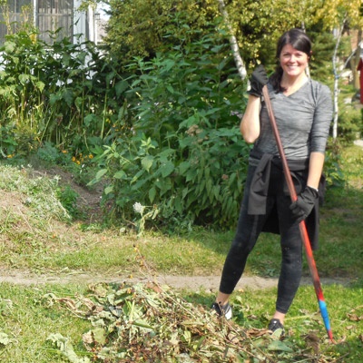 A woman stands with a rake, ready to garden.