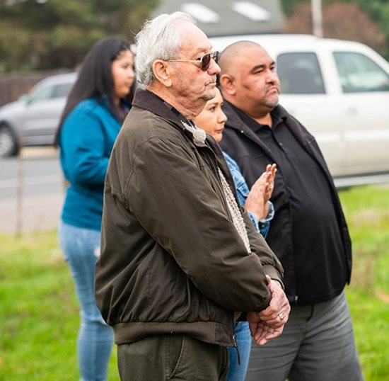 People stand quietly, waiting for the groundbreaking.