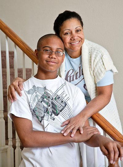 A black mother and her son stand on the stairs of their new home