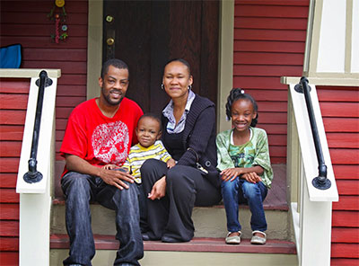 A black family sits on the porch of their new home