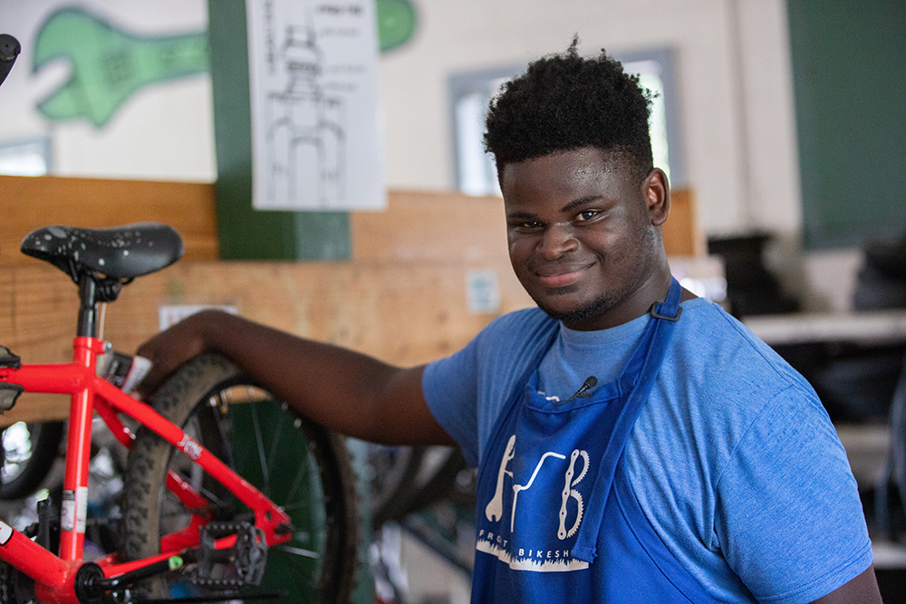 A black boy repairs one of his bikes at Dustin LaFont's shop