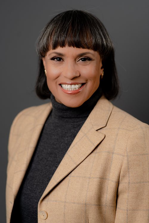 Susan M. Ifill smiles, wearing a tan blazer.