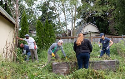 Staff and volunteers work to clear a yard.