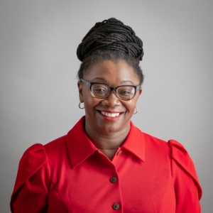 Angela Bannerman Ankoma, in a red top, smiles at the camera.