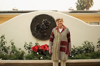 Jeanette Duncan stands outside a lovely garden.