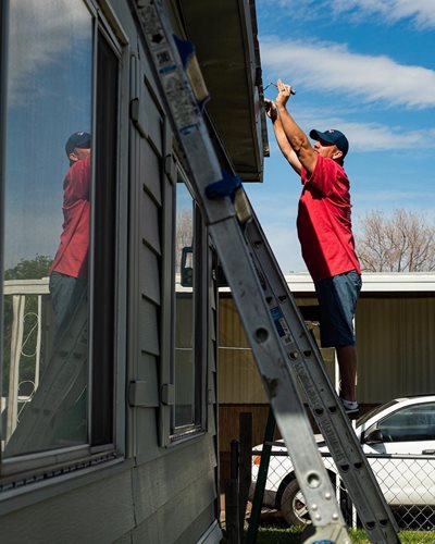 A man stands on a ladder, getting ready to pain the town.