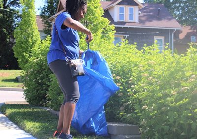 A volunteer picks up trash in her neighborhood as part of NeighborWorks Week.