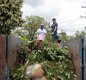 Volunteers stand on a mound of brush.