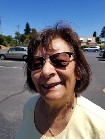 Mary Lucero of REACH smiles outside against a blue sky.