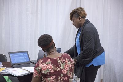 A housing counselor leans over the shoulder of a client.