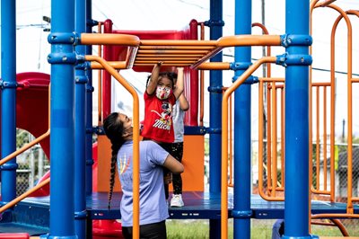 A student gets help from her teacher on the playground.