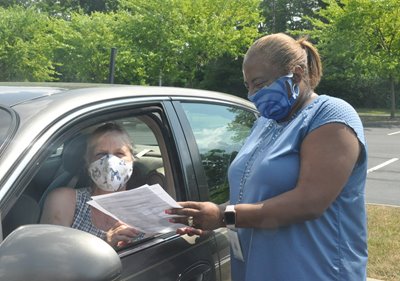 A woman drops of paperwork through the drive-thru set-up.