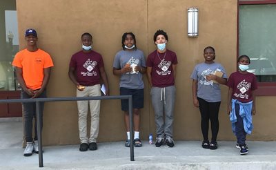 The kids who work on the mural post in front of a building.