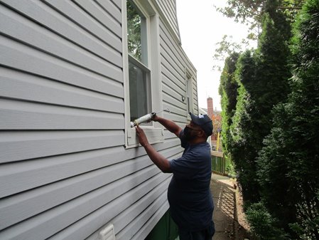 A volunteer helps weatherize a person's window