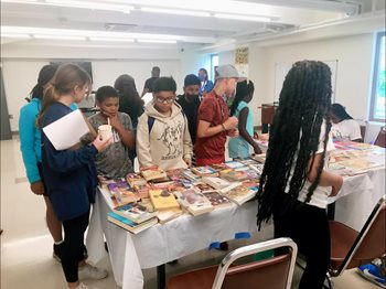 A group of students look at books, part of a CLI project.