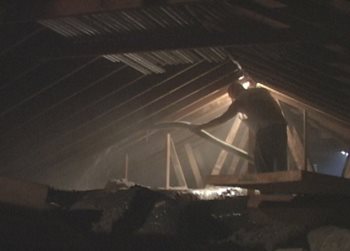 A worker puts insulation in an attic.