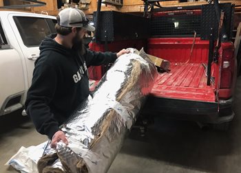 A worker holds a roll of insulation.