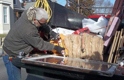 Caulking a window to weatherize a home.