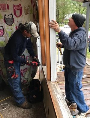 Workers fix a door frame to prepare for colder weather.