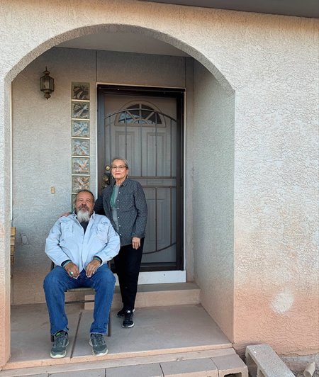 Ron and Karen Maldonado in front of their home in Arizona. They stand together in front of their front door.