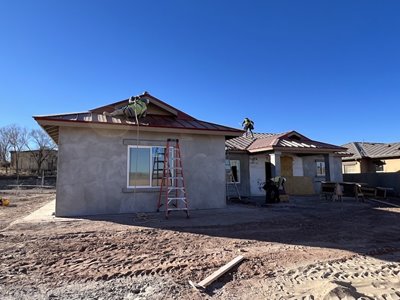 One of the homes being built by Clear Water. Ladders stand against the building and workers are on the roof putting on finishing touches.