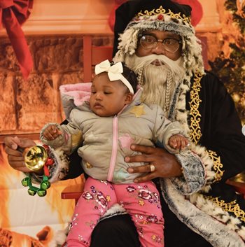 A little girl sits on the lap of a Santa Claus at the festival run by EANDC.