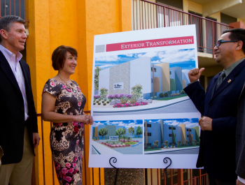 Two men and one women standing around a poster board blueprint of a new housing development.