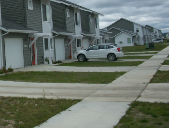 A line of row houses with a car parked in the driveway.