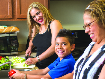 Two women and a young boy in a kitchen preparing food.