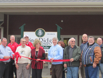 A group of white people stand in front of Pine Ridge living community for a ribbon cutting ceremony