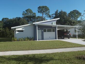 A newly renovated white house with a black car in the carport