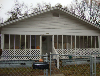 A dilapidated home with wire fencing and broken screens