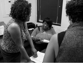 Three women talking in an office, black and white photo