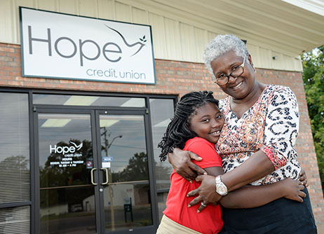 An older black woman and a child stand in front of Hope Credit Union