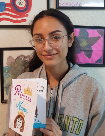 A teen girl wearing a gray hoodie holds up a card that says "Princess Nana" with a princess drawn on the front