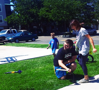 A young girl and a young boy, under the supervision of a teacher, take part in an experiment outside